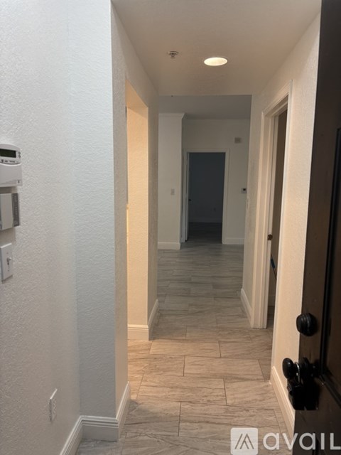 A hallway with tiled flooring and a black door on the right.
