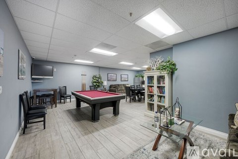 A room with a pool table, chairs, and a bookshelf.