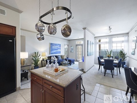 A kitchen with a black refrigerator and a dining table with chairs.