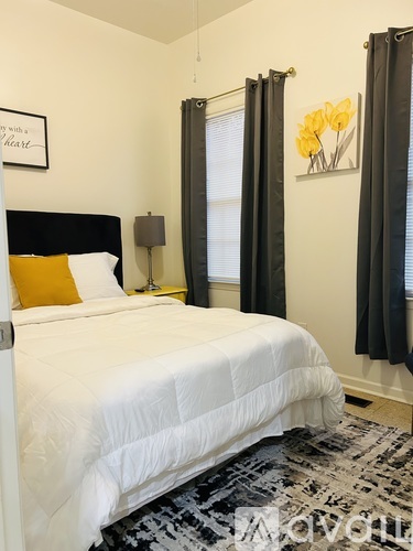 A bedroom with a white bed and a yellow pillow.