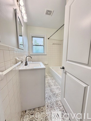 A white bathroom with a sink and a window.