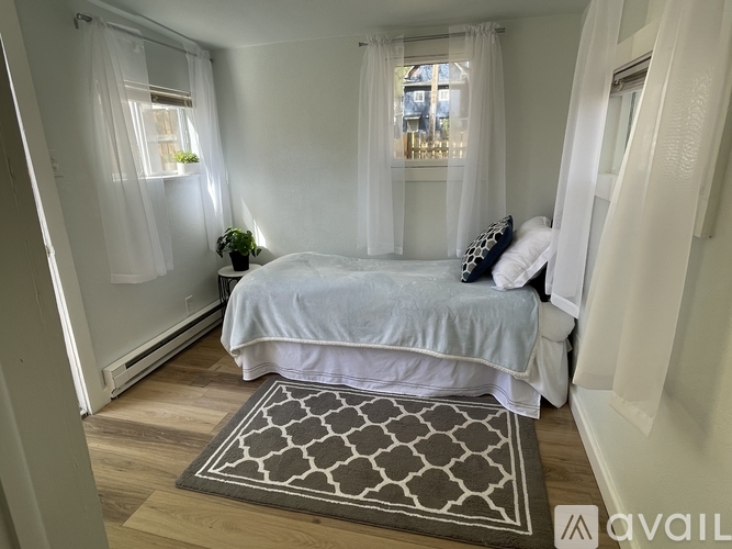 A bedroom with a bed, pillows, and a window with curtains.
