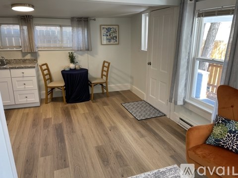 A dining area with a table set for two and a couch with a pillow on it.