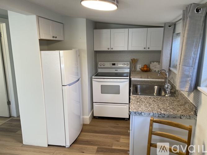 A kitchen with white appliances and wooden floors.