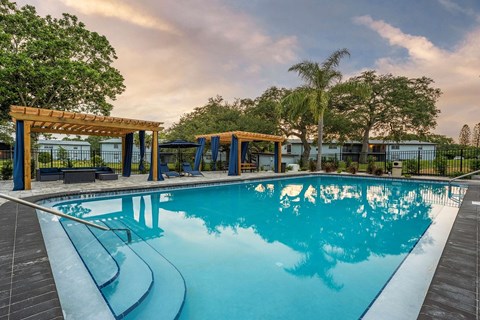A large outdoor swimming pool with a wooden pergola.