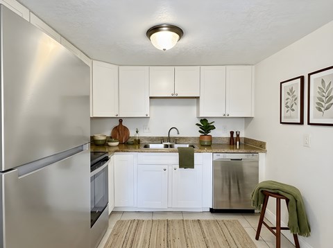 A kitchen with white cabinets and a stainless steel refrigerator.