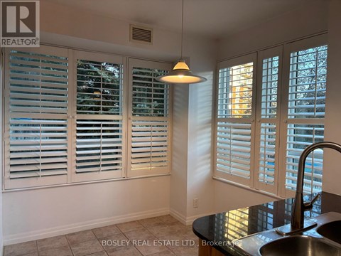 A kitchen with a sink and a window with white shutters.
