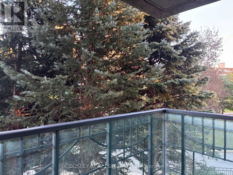 A glass balcony with a tree in the background.