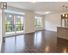 A spacious room with wooden flooring and a large window overlooking a garden.