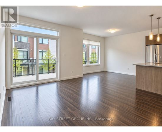 A spacious room with wooden flooring and a large window overlooking a garden.