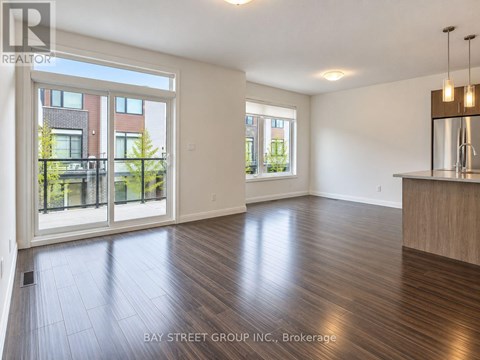A spacious room with wooden flooring and a large window overlooking a garden.