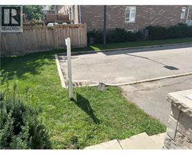 A sign that says REALTOR is on a post in the grass.