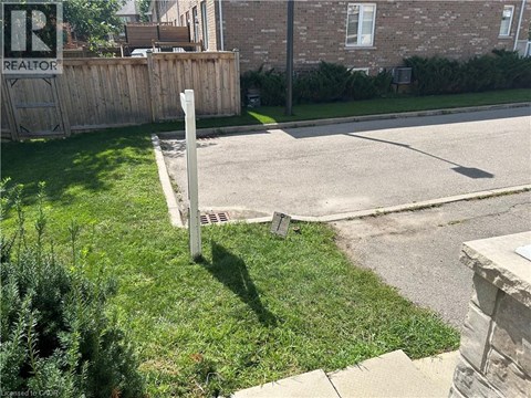 A sign that says REALTOR is on a post in the grass.