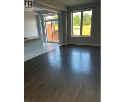 A room with wooden floors and a sliding glass door leading to a backyard.