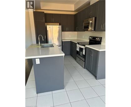A kitchen with a white counter top and a stainless steel refrigerator.