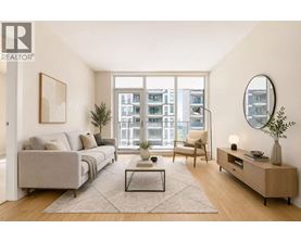 A living room with a grey couch, a coffee table, a chair, a side table, and a large window.