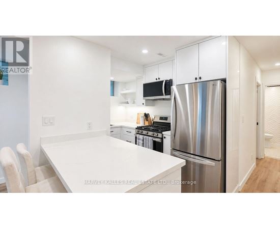 A modern kitchen with a white table and stainless steel appliances.