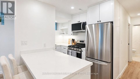 A modern kitchen with a white table and stainless steel appliances.