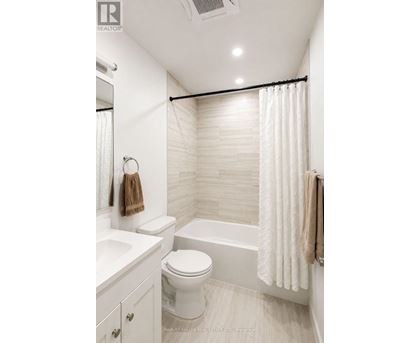 A white bathroom with a toilet, sink, and shower.