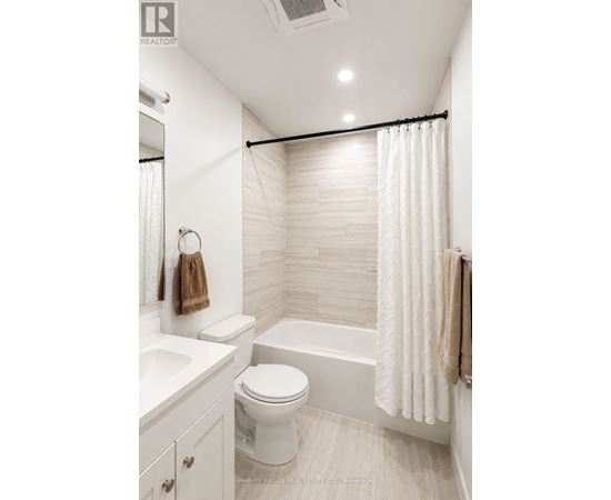 A white bathroom with a toilet, sink, and shower.