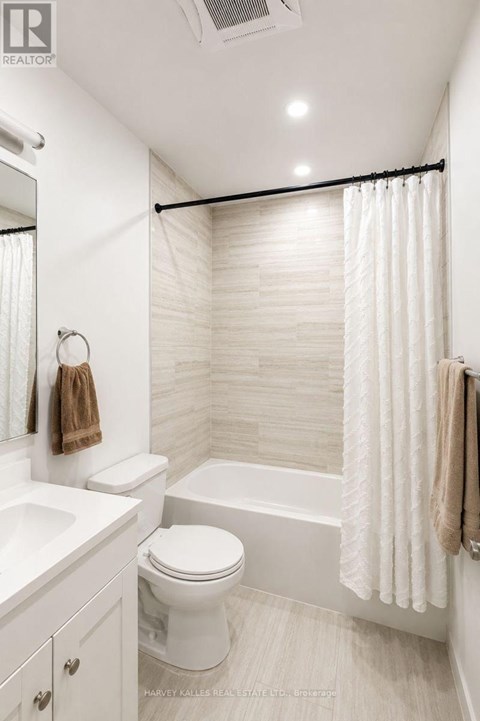 A white bathroom with a toilet, sink, and shower.