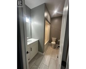 A bathroom with a toilet, sink, and mirror.