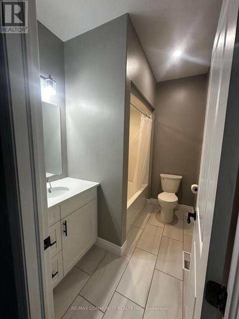 A bathroom with a toilet, sink, and mirror.