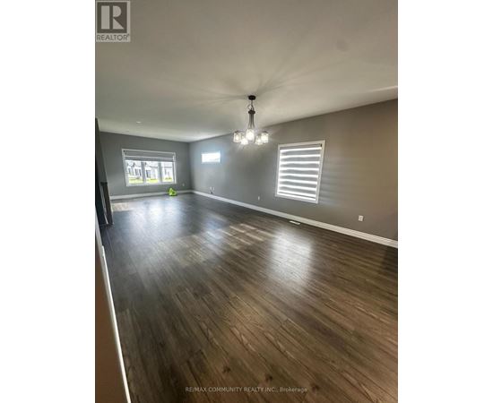 A spacious room with wooden flooring and a chandelier hanging from the ceiling.