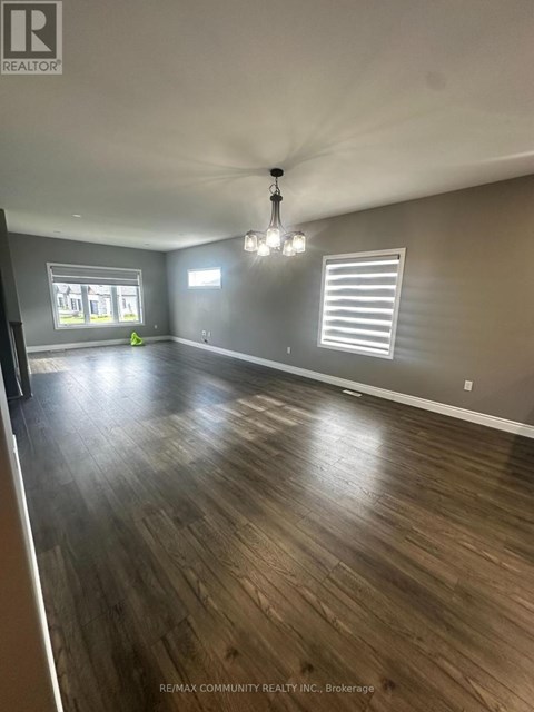 A spacious room with wooden flooring and a chandelier hanging from the ceiling.