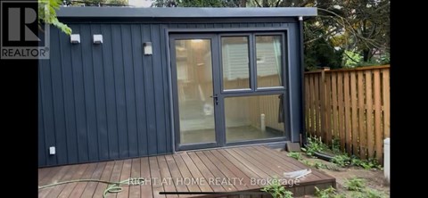 A small house with a glass door and a wooden deck.
