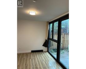 A room with a sliding glass door and a black jacket hanging on the door.
