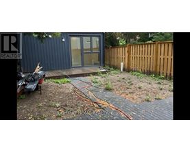 A backyard with a wooden fence and a small building with a glass door.