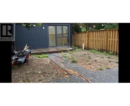 A backyard with a wooden fence and a small building with a glass door.