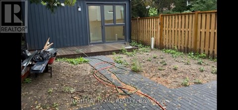A backyard with a wooden fence and a small building with a glass door.