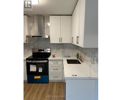 A kitchen with a stove top oven and white cabinets.