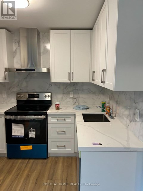 A kitchen with a stove top oven and white cabinets.