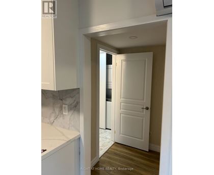A white door is in a hallway with a marble counter top.