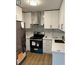 A kitchen with a refrigerator, oven, and cabinets.