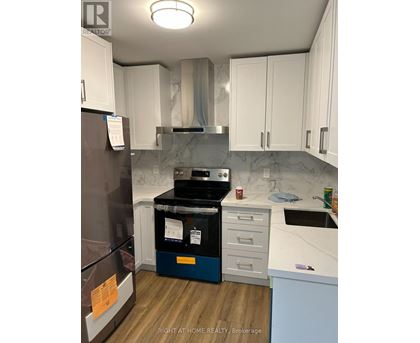A kitchen with a refrigerator, oven, and cabinets.