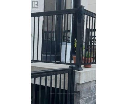 A black metal railing with a stone pillar and a potted plant.