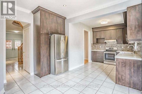 A kitchen with a refrigerator, oven, and sink.