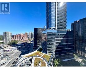 A tall building with a glass facade stands in the foreground of a cityscape.