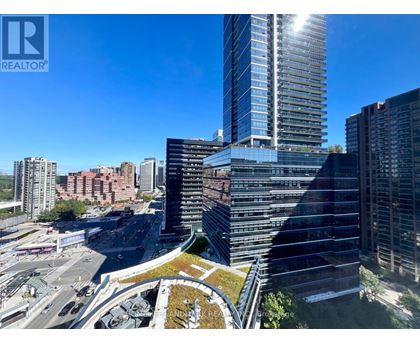 A tall building with a glass facade stands in the foreground of a cityscape.
