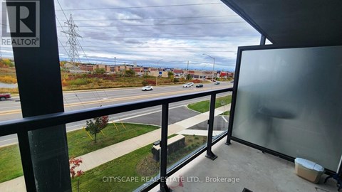 A view from a balcony overlooking a street with cars and buildings.