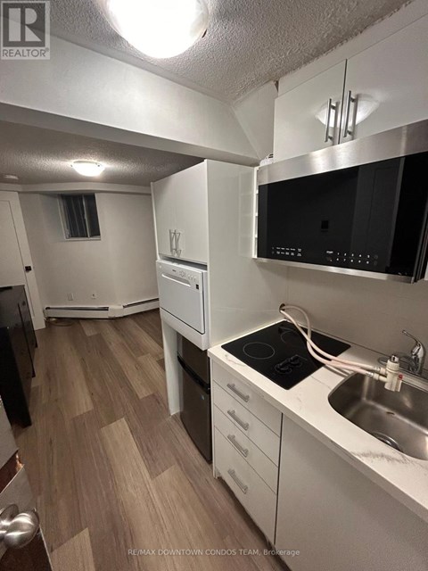 A kitchen with a stove top oven, microwave, and sink.