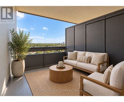 A living room with a couch, chair, and table with a view of the city.