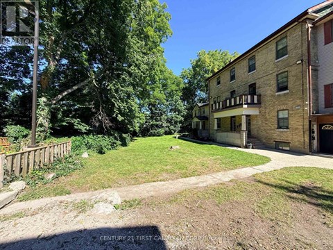 A tree-lined yard with a building in the background.