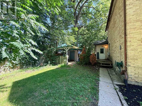 A backyard with a white fence and a green lawn.