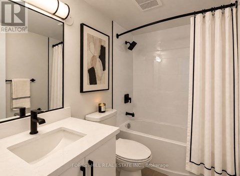 A white bathroom with a sink, toilet, and shower.