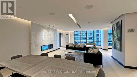 A spacious office with a long table and chairs, a couch, and a TV mounted on the wall.